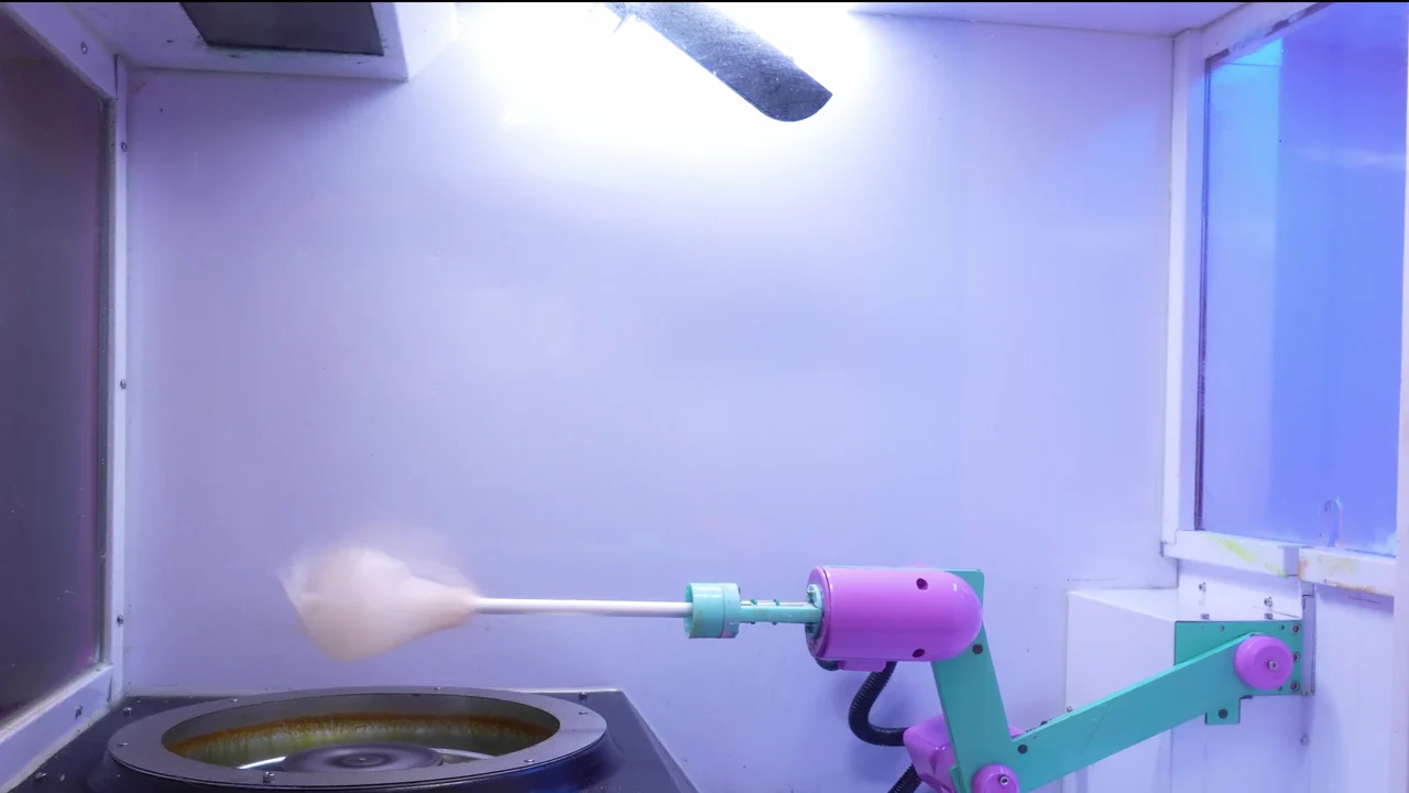 Inside the Futureino Cotton Candy Robot: the robotic arm spinning a fresh cone of floss above the heated sugar pan