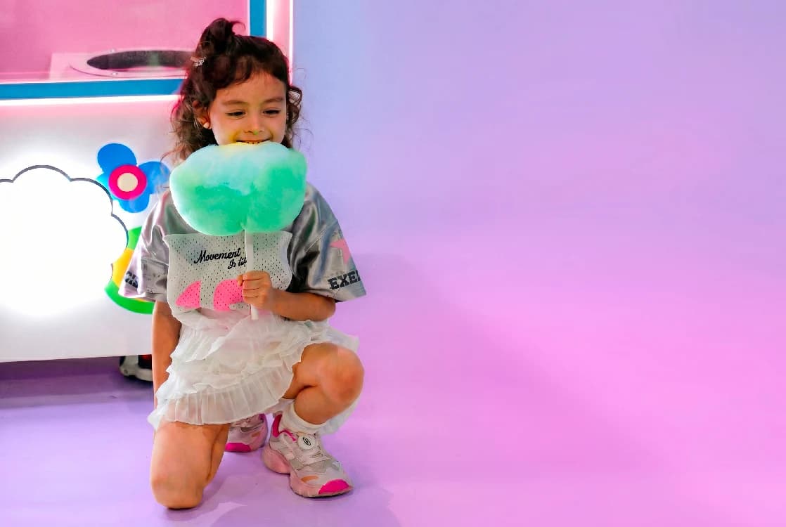 Girl tasting fresh mint cotton candy beside the machine