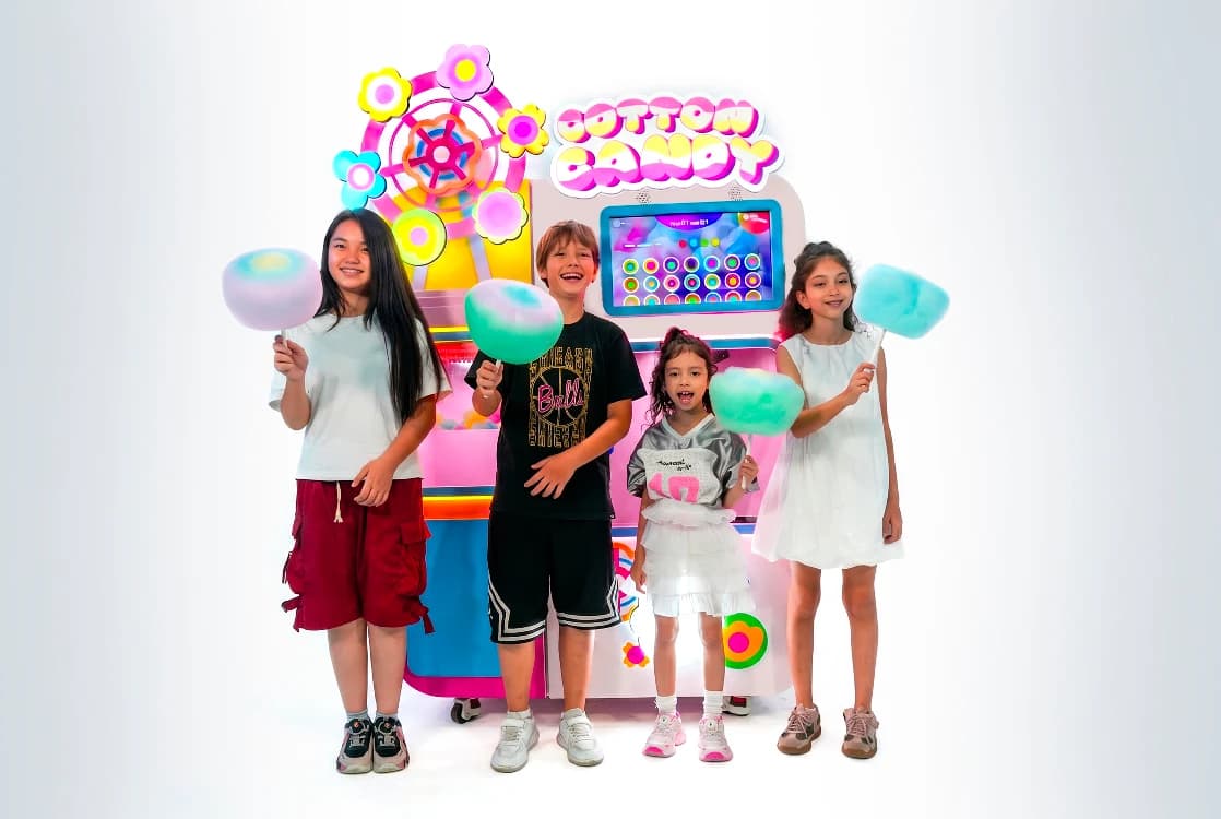 Four kids holding fresh cotton candy in front of the Futureino cotton candy vending machine