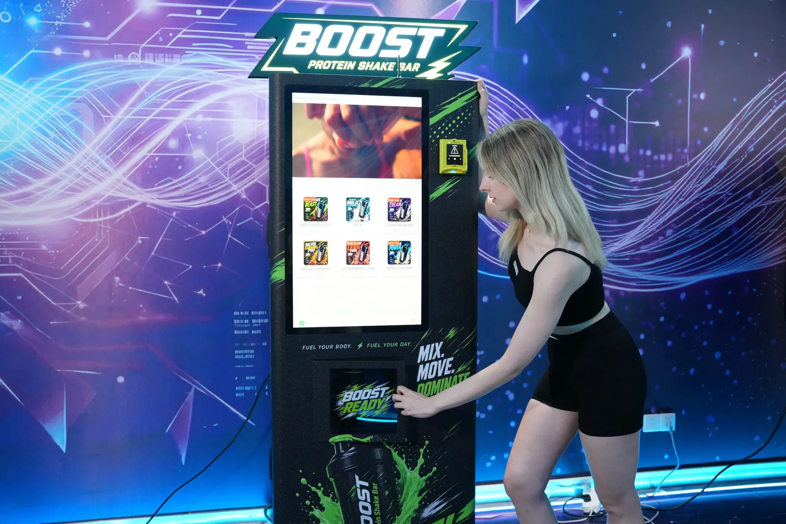 Customer using the touchscreen and card reader on a Futureino Boost protein shake vending machine, the two parts of the machine that depend on a connection