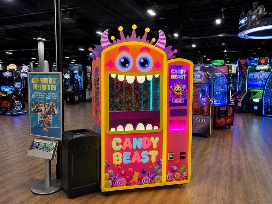 Futureino Candy Beast vending machine installed on the floor of a busy family entertainment arcade beside other games