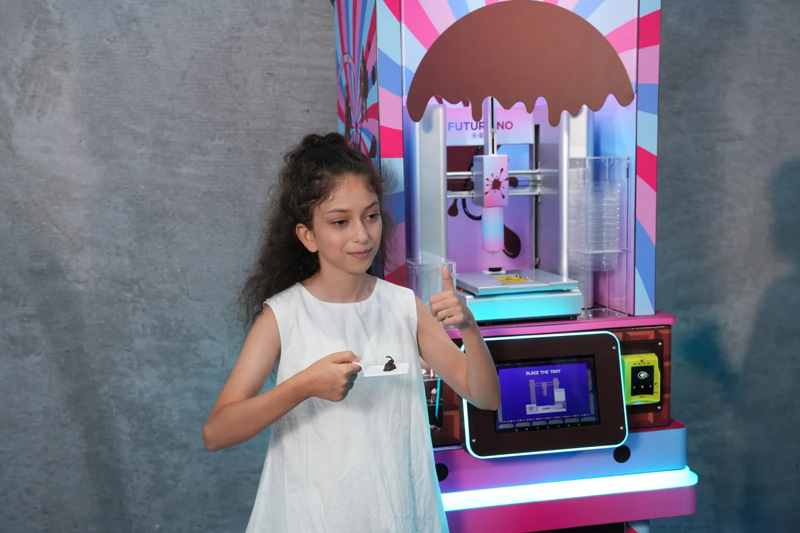 Girl tasting her 3D-printed chocolate next to the ChocoArt machine