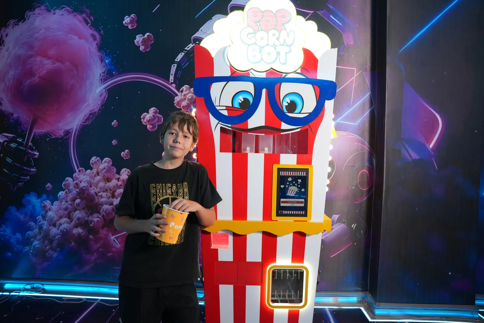 Boy enjoying popcorn next to the Popcorn Bot machine in the showroom